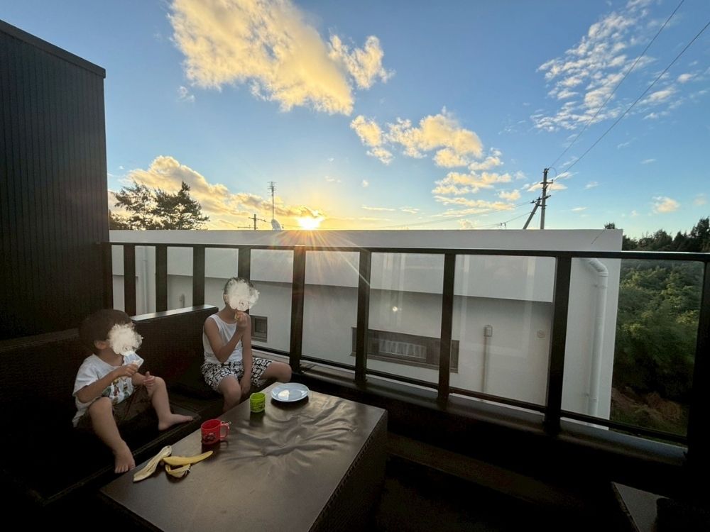 ベランダで朝食をとる子供たちと、朝日。