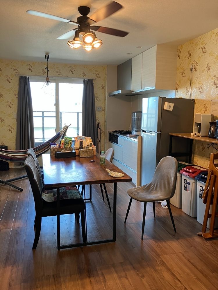 リビングにはダイニングテーブルと椅子や冷蔵庫などの家電があり、窓際にはハンモックも配置されている。